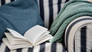 A striped sofa with a book and a green knitted blanket.