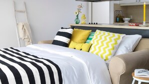 A bed with a striped bedspread, a bedside table with a book, and a chair with a cushion. - Penthouse in Loosdrecht (Loosdrecht)