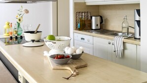A modern kitchen with white cabinets, a stainless steel range hood, a coffee maker, and various kitchen items on the counter. - Penthouse in Loosdrecht (Loosdrecht)
