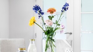A dining table with a vase of flowers, a milk bottle, and a jar of spices. - Watervilla in Loosdrecht (Loosdrecht)