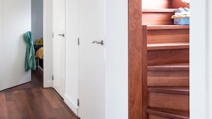 A hallway with a wooden staircase, white doors, and a visible bathroom with a towel hanging. - Watervilla in Loosdrecht (Loosdrecht)