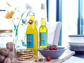 A breakfast setting with two bottles of olive oil, a bowl of cherries, and a stack of cookies on a wooden board. - Panorama 2DT in Loosdrecht (Loosdrecht)