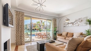 A modern living room with a fireplace, a sofa, a coffee table, and a TV mounted on the wall. - Waterside marina view 3 bedroom apartment with private pool in Puerto Sotogrande (San Roque)