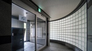 Un corridoio con una parete di vetro curva, un ingresso con porta in vetro e un soffitto con luci a incasso.