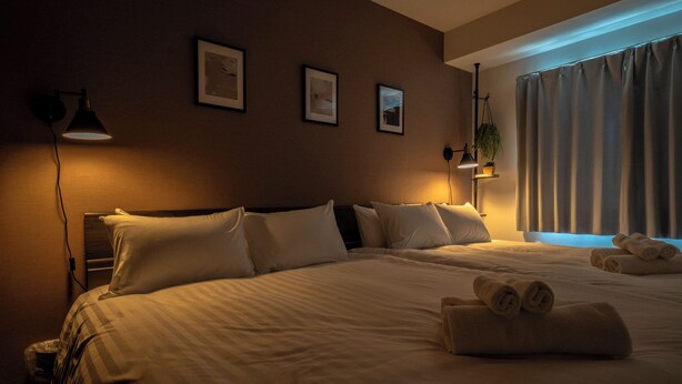 Una camera d'albergo con un letto grande, due comodini, una lampada a parete e una finestra con tende.