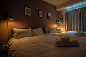 A hotel room with a large bed, two bedside tables, a wall-mounted lamp, and a window with curtains. - Norwegian Wood 303 (Sapporo)