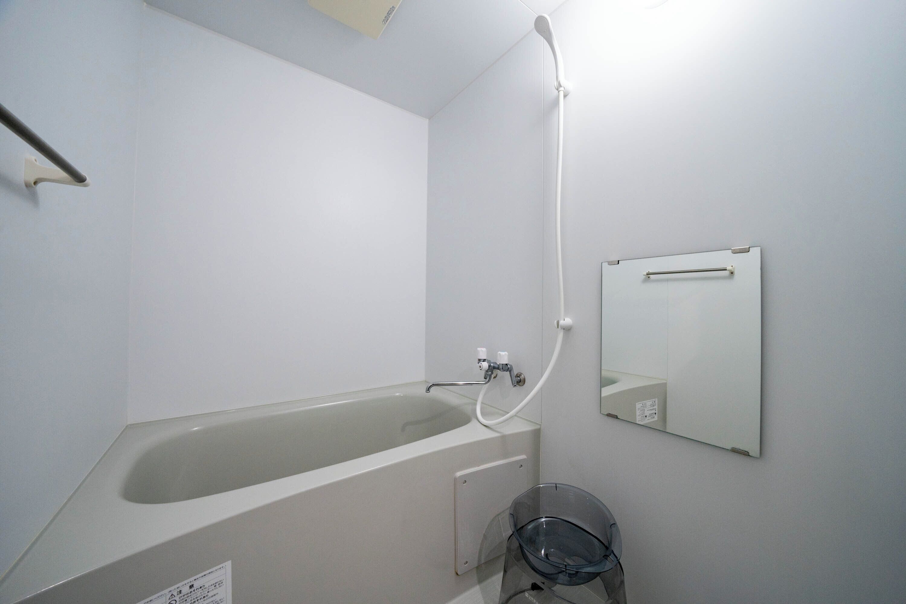 Une salle de bain avec une baignoire, une douche, un miroir et une porte en verre.