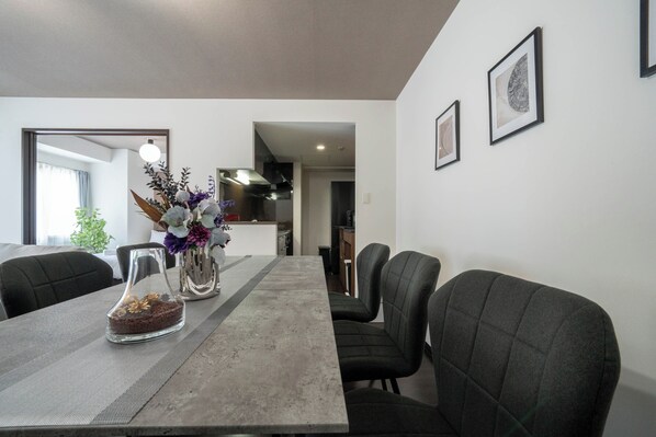 A dining area with a long table, chairs, and a vase with flowers.