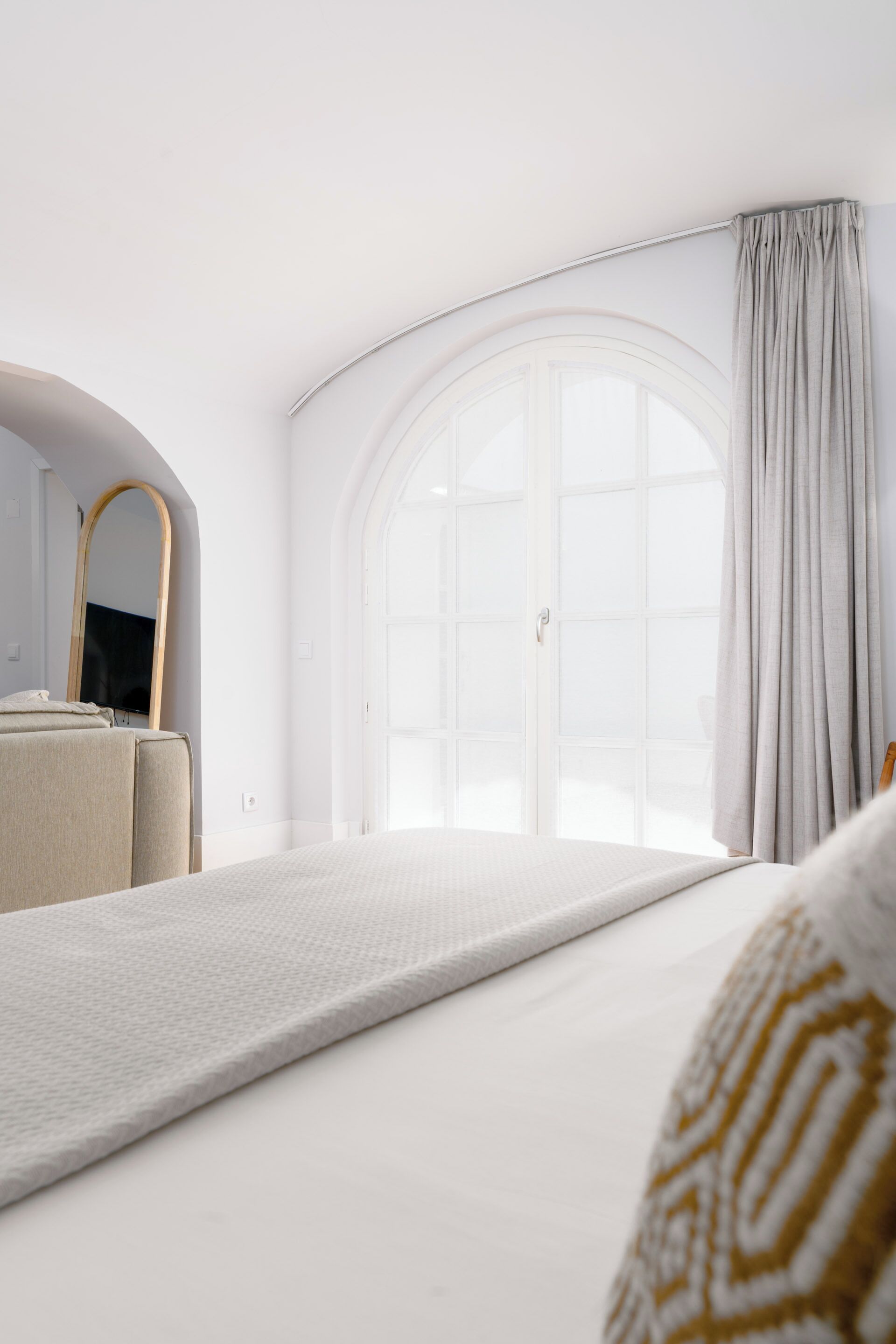 Une chambre moderne avec une grande fenêtre, un lit, un miroir et un téléviseur.