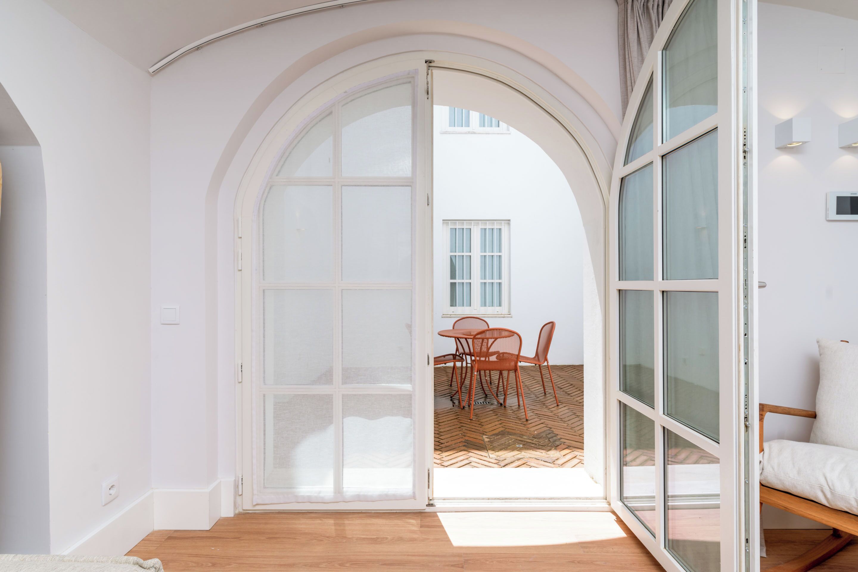 Una habitación con un amplio arco de entrada que da a un espacio exterior con zona de estar y suelo con motivo de espiga.