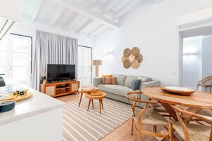 Uma sala de estar moderna com TV, sofá e área de refeições.