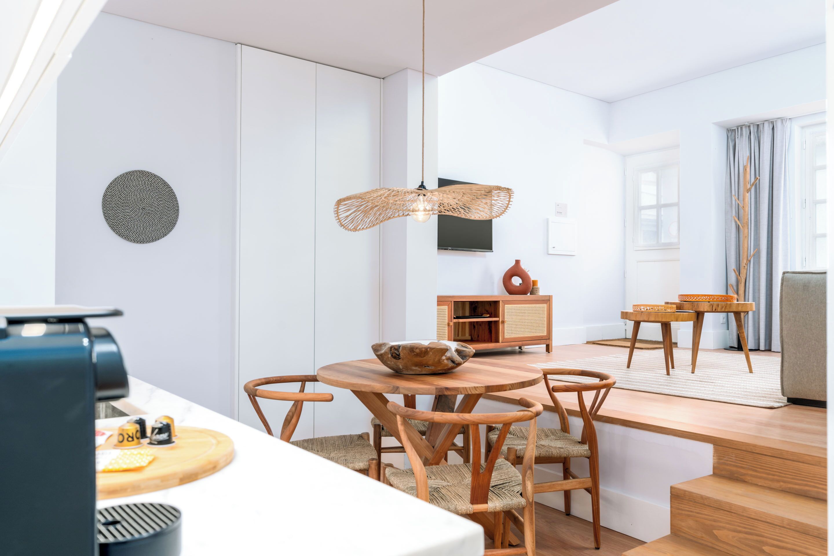 Una cocina moderna con armarios blancos, una mesa de comedor de madera y una lámpara colgante.