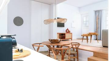 Una cocina moderna con armarios blancos, una mesa de comedor de madera y una lámpara colgante.