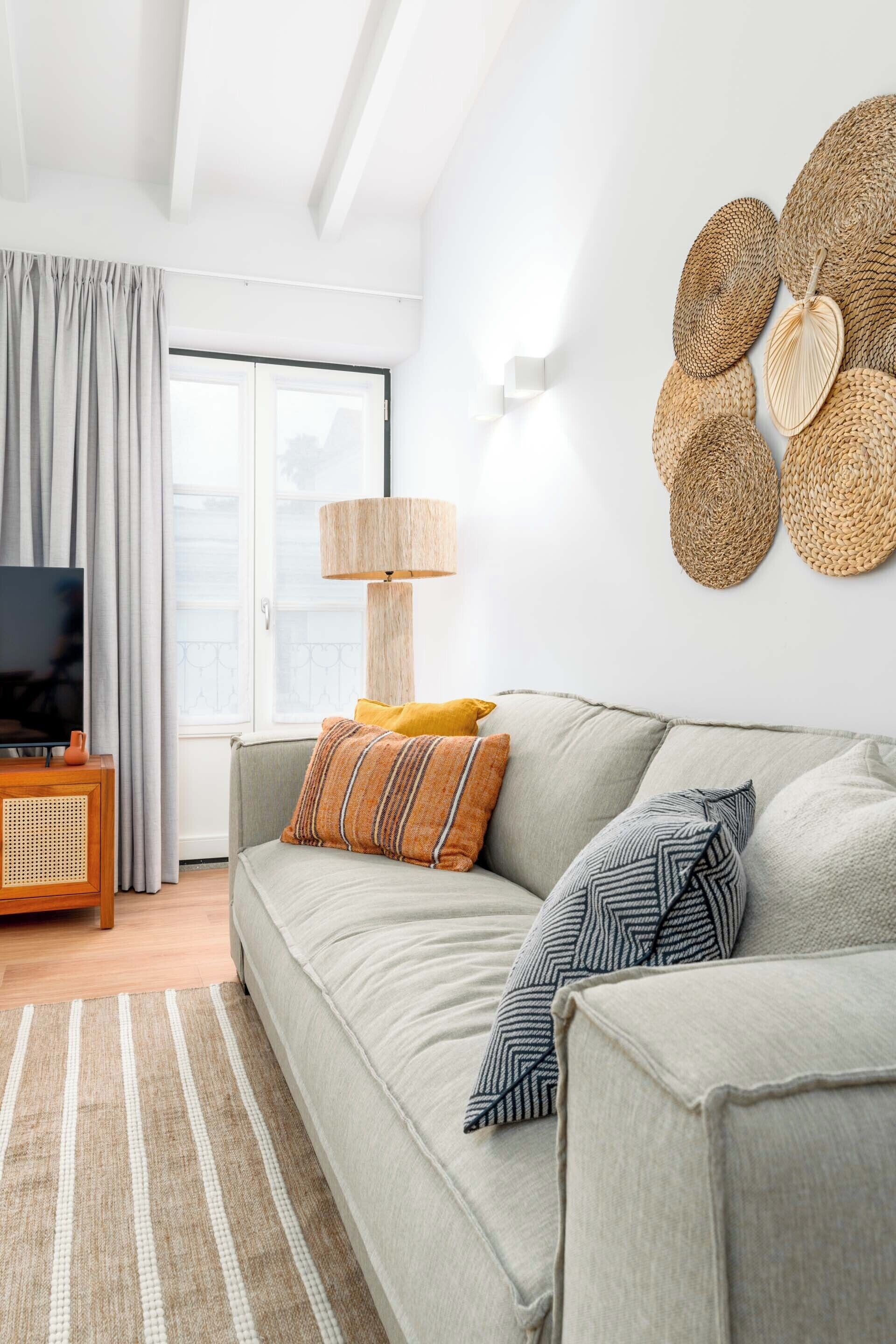 A modern living room with a sofa, cushions, a television, a lamp, and a wall art piece.