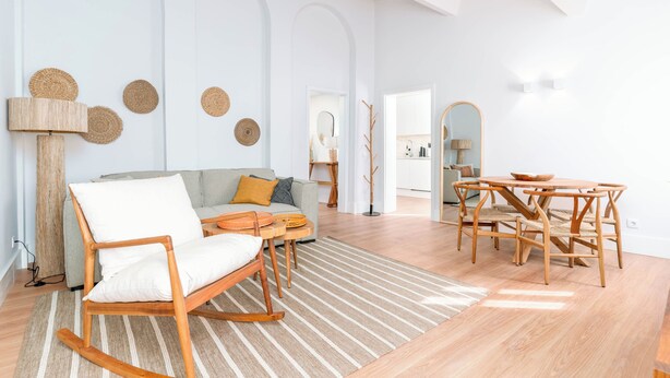 A modern living room with a sofa, a rocking chair, a dining table with chairs, and a lamp. - Limehome Evora Rua de Machede 52 (Évora)