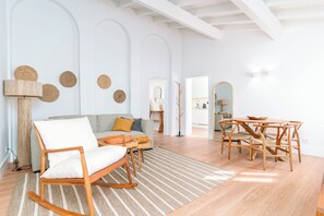 A modern living room with a sofa, a rocking chair, a dining table with chairs, and a lamp. - Limehome Evora Rua de Machede 52 (Évora)