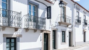A white building with a tiled roof, a sign reading "Limehouse," and a cobblestone street. - Limehome Evora Rua de Machede 52 (Évora)