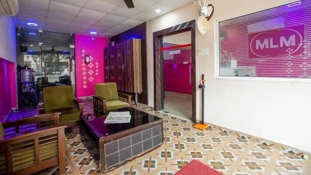 A hotel lobby with a ceiling fan, a reception desk, and a large window with the logo "MLM". - Terra Hotels T nagar (Chennai)