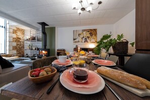 Un comedor con una mesa dispuesta para el desayuno, que incluye pan, fruta y bebidas.