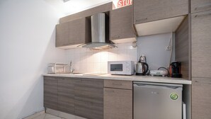 A modern kitchen with wooden cabinets, a stainless steel range hood, a microwave, a coffee maker, and a dishwasher. - Kastella cozy flat for 2 persons my MPS (Pireas)