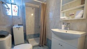 A bathroom with a toilet, shower, sink, and a glass-enclosed vanity with towels. - Kastella cozy flat for 2 persons my MPS (Pireas)