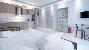 A modern hotel room with a bed, a small kitchenette, a bathroom, and a TV mounted on the wall. - Kastella cozy flat for 2 persons my MPS (Pireas)