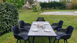 A rectangular outdoor table set for six with black chairs, surrounded by a grassy area and a hedge. - Nature, spacious, fenced, well equipped, Loire castles, ideal for families (Selles-sur-Cher)