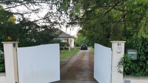 A gated driveway leading to a house with a car parked on the road. - Nature, spacious, fenced, well equipped, Loire castles, ideal for families (Selles-sur-Cher)