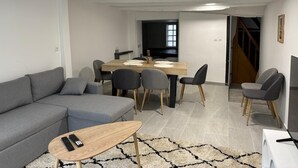 A modern living room with a grey sofa, a wooden coffee table, and a TV in the background. - 2 Bedroom Private vacation home in Amboise (Amboise)