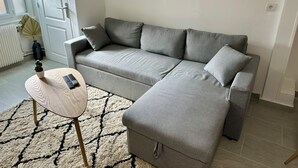 A modern living room with a grey sectional sofa, a small round coffee table, and a patterned rug. - 2 Bedroom Private vacation home in Amboise (Amboise)