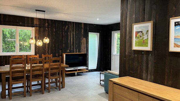 A modern living room with a wooden dining table, chairs, a flat-screen TV, and a sofa. - 2 self-contained country homes with heated indoor swimming pool 8-12p (Aix-en-Issart)