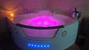 Un jacuzzi con iluminación rosa, un panel de control y un cubo con una botella.
