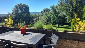 Un patio al aire libre con una mesa y sillas, rodeado por una cerca de madera y diversas plantas.