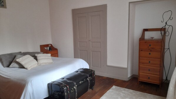 A bedroom with a bed, a dresser, a suitcase, and a door. - Le Clos de Soulages Gite 4 Personnes (Palmas d'Aveyron)