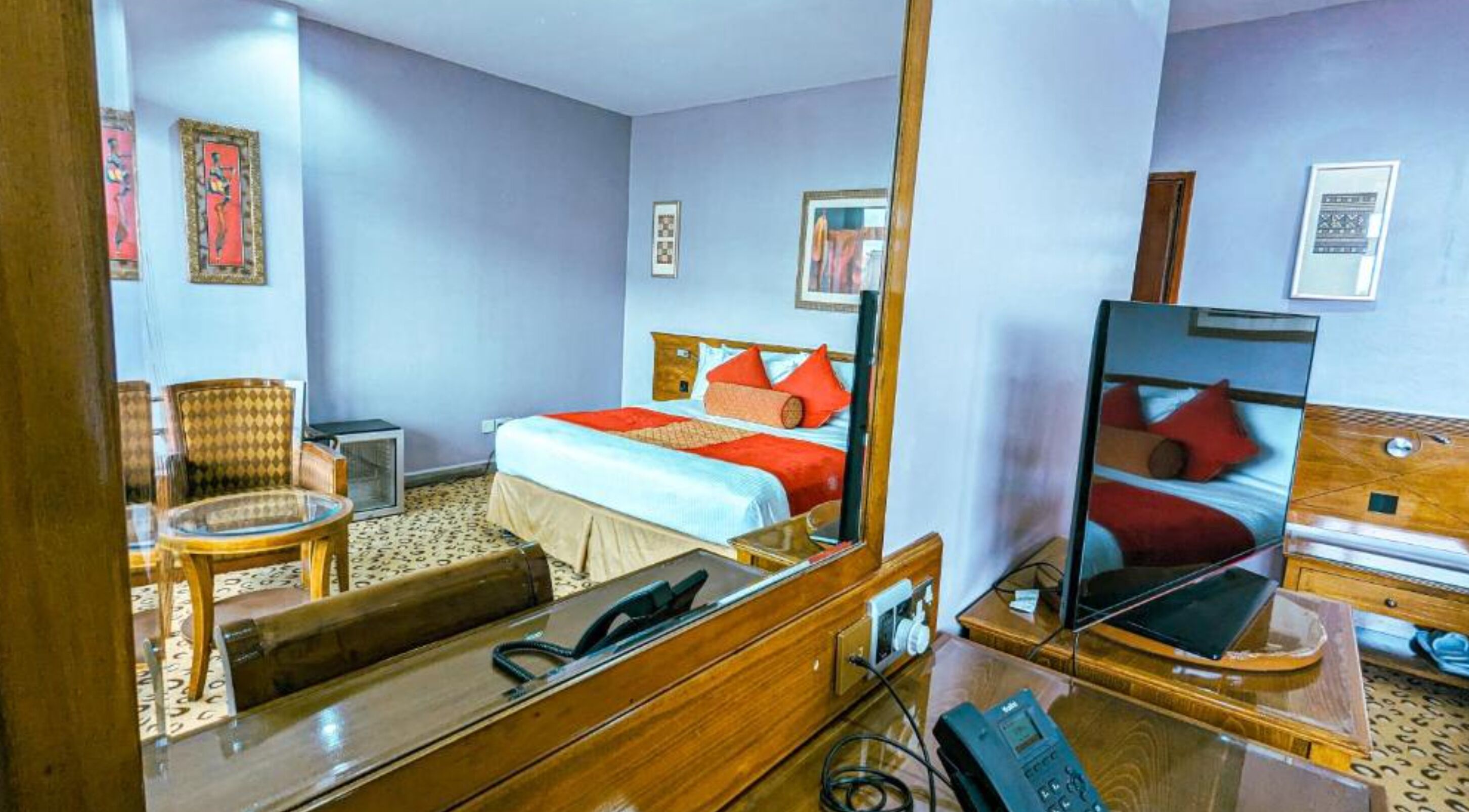 Une chambre d’hôtel avec un lit, une chaise, un bureau et un miroir.