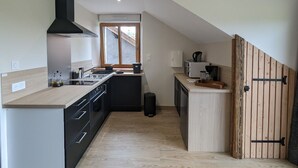Une cuisine moderne dotée d’un îlot central, de meubles de rangement noirs et d’une porte en bois.