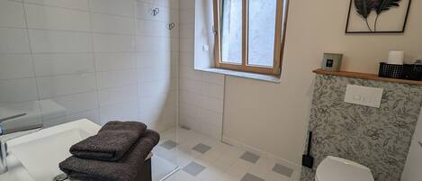 A bathroom with a shower, toilet, and sink.