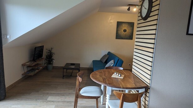 Un espace de vie de style loft comprenant un coin repas, un canapé bleu, un panneau mural en bois et une horloge.