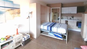 A bedroom with a bed, wardrobe, and a small kitchenette.