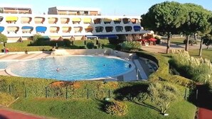 A swimming pool surrounded by well-maintained lawns and a building with multiple balconies.