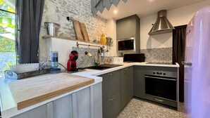 Une cuisine moderne avec des meubles gris, un évier en acier inoxydable, un four à micro-ondes et une cuisinière.