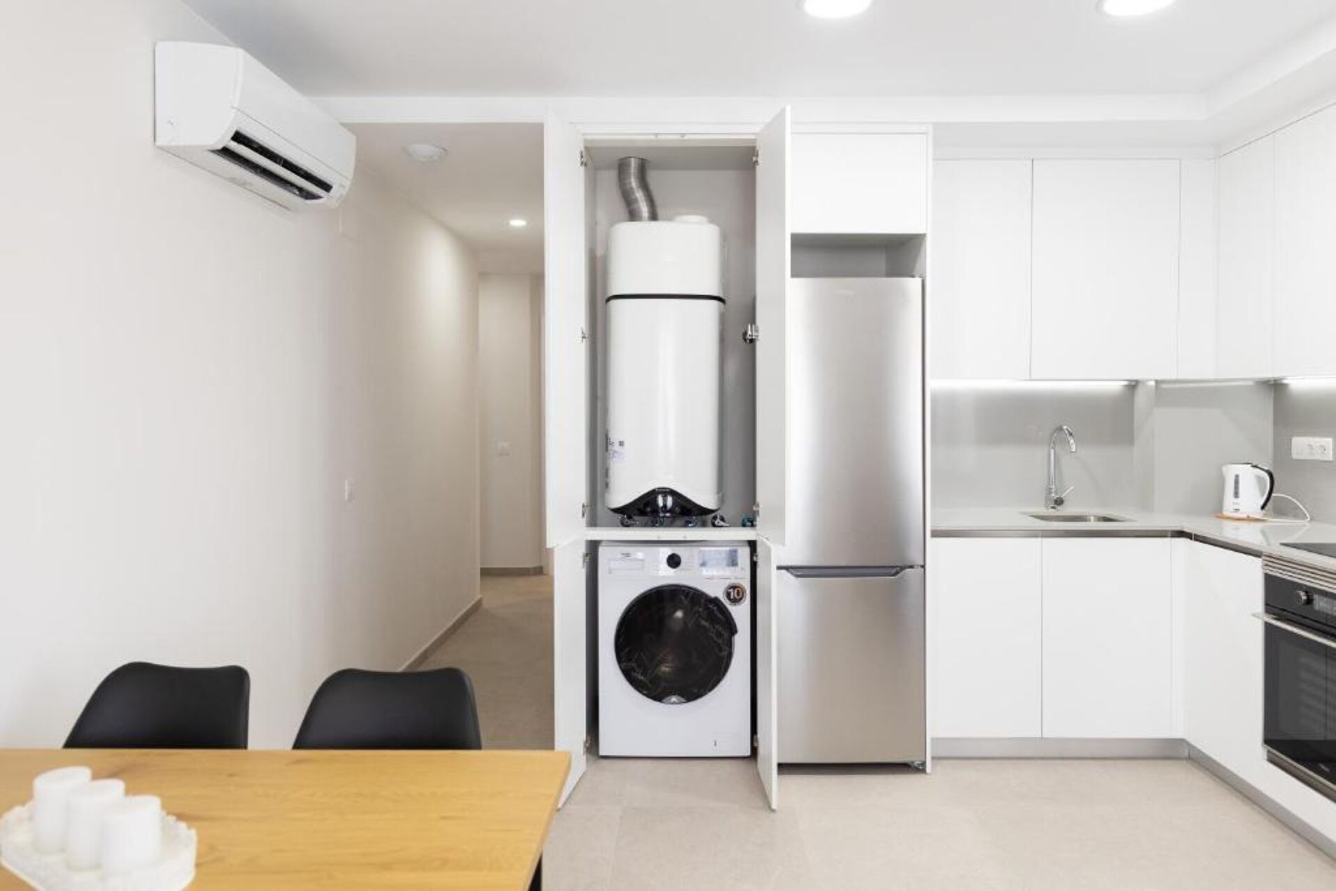 Cocina compacta con lavadora y secadora integradas, un lavaplatos y una estufa.