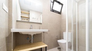 A bathroom with a sink, toilet, and shower area.