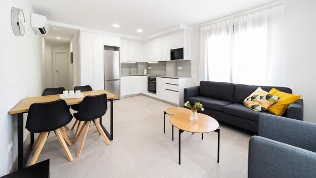 A modern apartment with a dining area, kitchen, and living room.