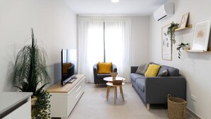 Una sala moderna con televisor, sofá y comedor.