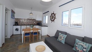 A compact living space with a kitchen, dining area, and a sofa with nautical-themed cushions. - Fischer Home Roque del Este (Punta Mujeres)