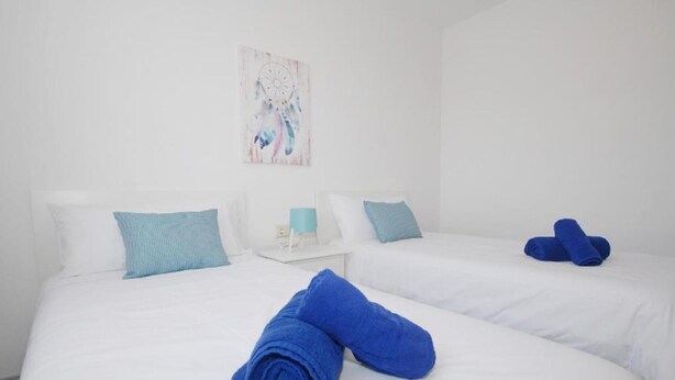 A hotel room with two beds, white bedding, and blue towels. - Calma Suites La Garita B6 (Arrieta)