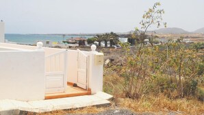 A coastal property with a white building, a view of the sea, and sparse vegetation. - Calma Suites La Garita B6 (Arrieta)