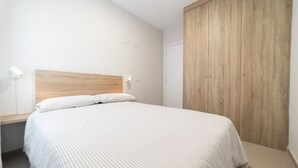 Un dormitorio con cama, cabecera de madera, armario y lámpara de noche.
