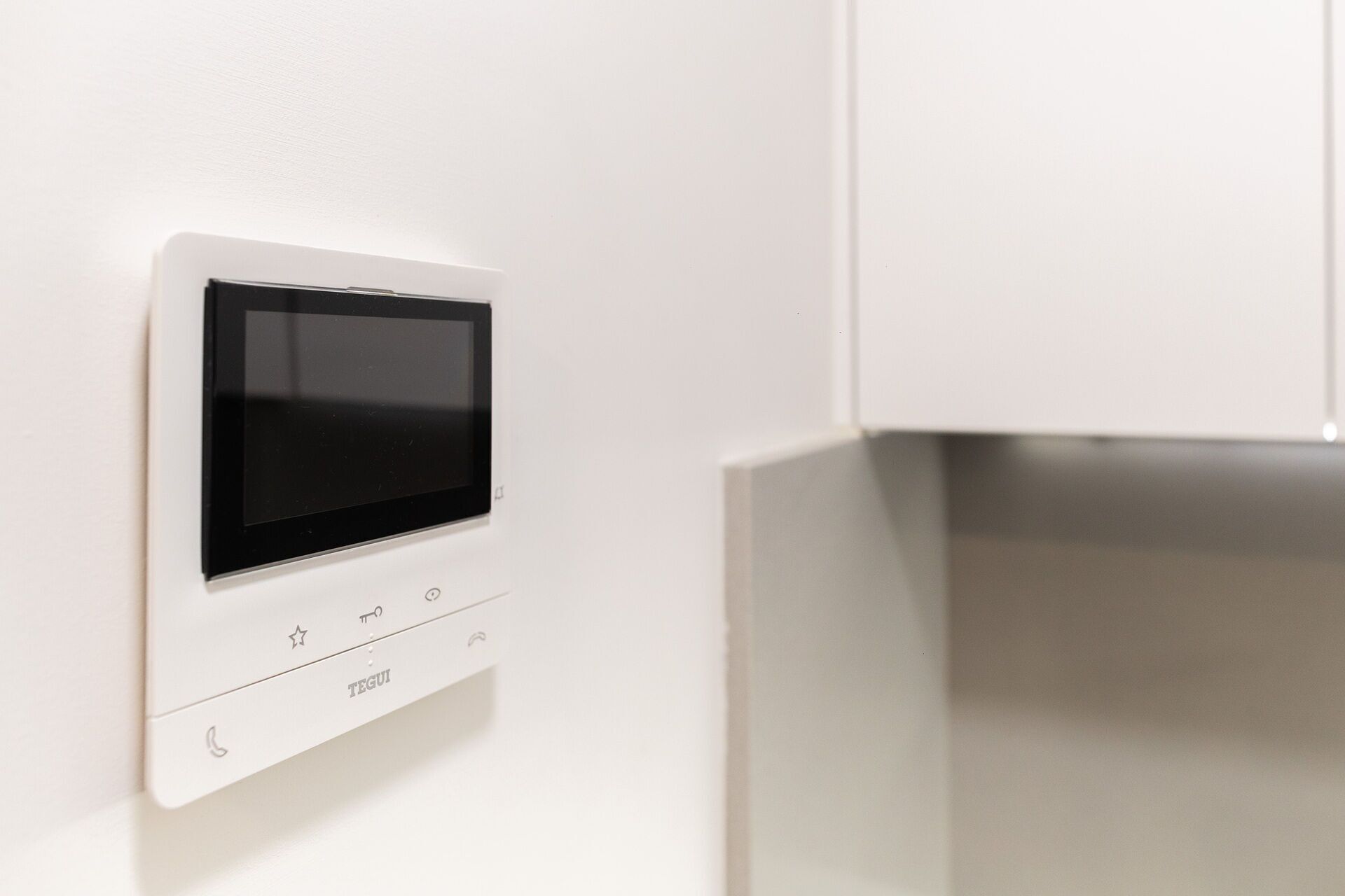 Panel de control montado en la pared con pantalla y varios botones, probablemente para un sistema de domótica.